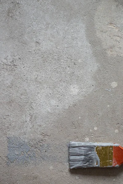 A red paint brush lies on a gray background. Concrete.