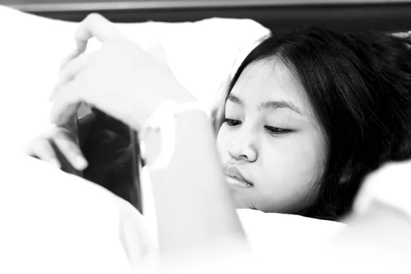 cute teenage girl with smartphone on bed