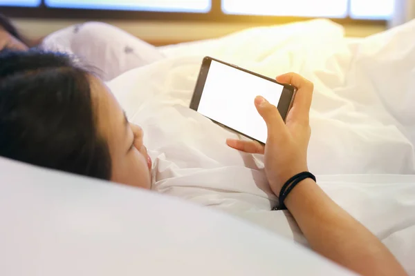 cute teenage girl with smartphone on bed in the morning