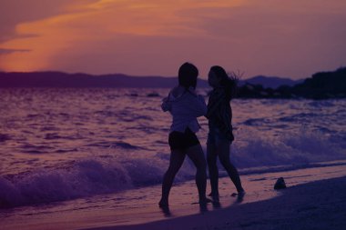 Mutlu kız sahilde günbatımı sırasında yürüyüş 