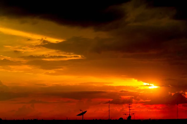 衛星皿と通信ポールのシルエットと夕焼けの背景の光 — ストック写真