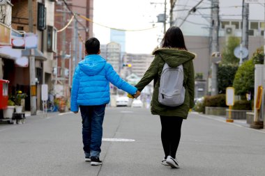 Erkek ve kız çocuk el ele yolda yürürken.