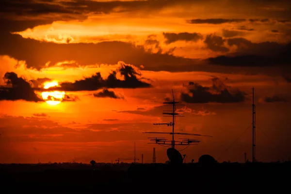 衛星皿と通信ポールのシルエットと夕焼けの背景の光 — ストック写真