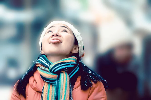 woman enjoy and play on the snow with tongue catches snow on the street