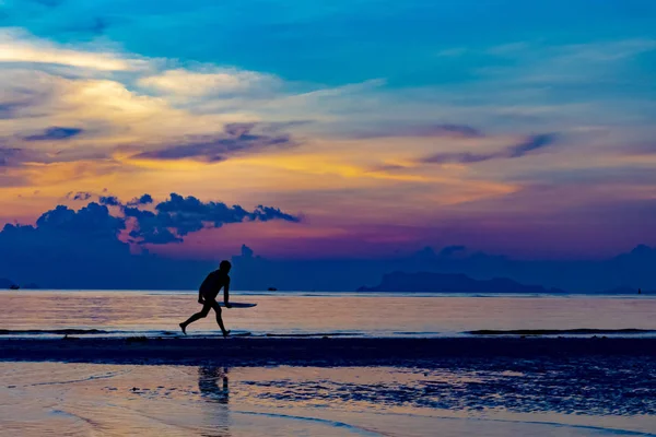 夕暮れの空とビーチでサーフボードを持つ男のシルエット . — ストック写真