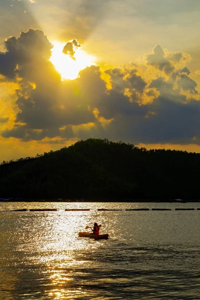 女の子は湖でカヤックをしていて、山の後ろの夕日 — ストック写真