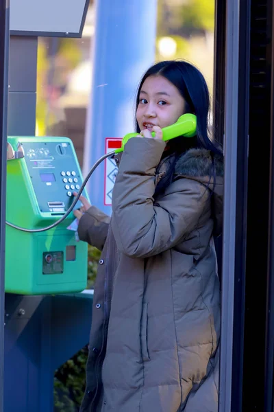 Junge asiatische teen mit einem Anruf auf die öffentliche Telefon lizenzfreie Stockbilder