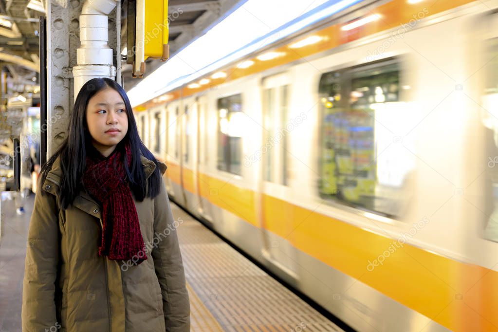 girl stand at high speed train station waiting for train