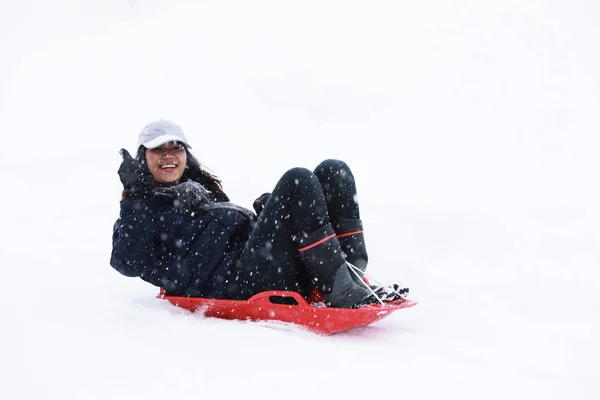 Boldog Ázsiai tini játszik piros szán a hó, Gala Yuzawa. Japa — Stock Fotó