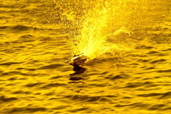 Velocidade: o pequeno barco de brinquedo que corre através da água durante o — Fotografia de Stock