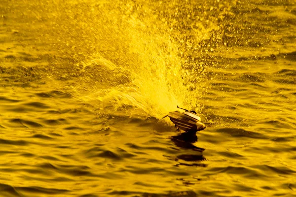 Velocidade: o pequeno barco de brinquedo que corre através da água durante o — Fotografia de Stock