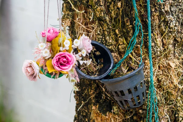 Τεχνητά λουλούδια σε γλάστρες κρέμονται στο δέντρο. — Φωτογραφία Αρχείου