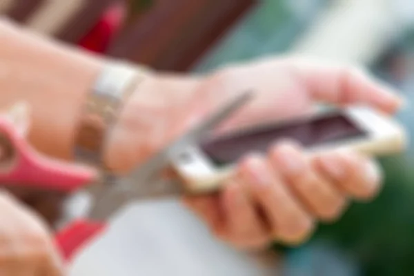 Blurry of hand holding scissors and cut mobile phone. — Stock Photo, Image