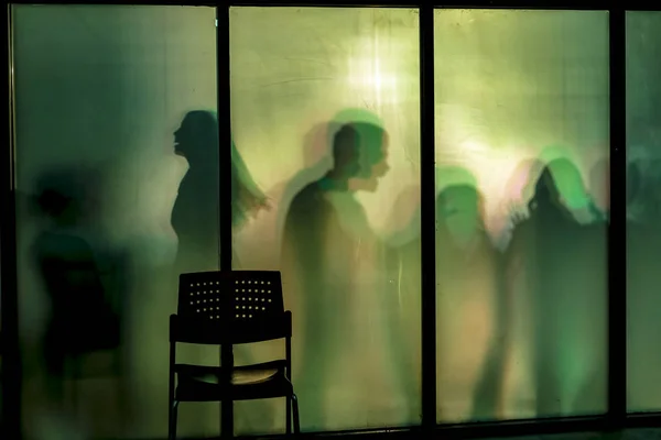 illuminated silhouettes of people by windows with chair