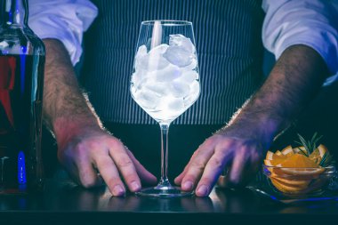 Barmen bir barın arkasında duruyor, gece kulübünde çalışırken kokteyl hazırlıyor.