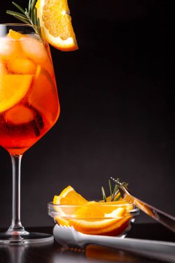 Bir bardağa portakal ve biberiye dilimleriyle süslenmiş bir bardak şampanya ve portakal likörü kokteyle servis edilir.