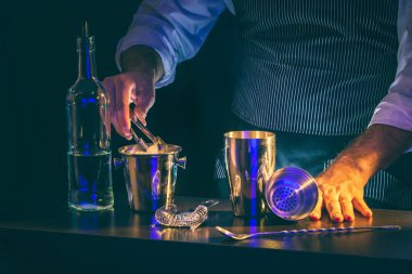 Barmen kokteyl hazırlıyor. Kokteyl kutusuna buz küpleri koyuyor.