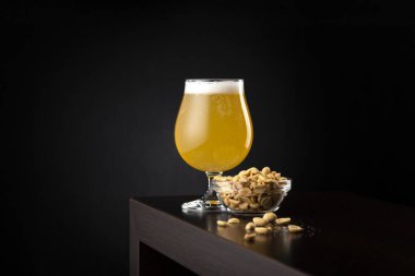 Bir bardak soğuk limonlu meyve birası ve bir kase tuzlanmış fıstık tezgahta fotokopi alanı ile birlikte.