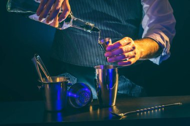 Barmen kokteyl hazırlıyor, şişeden votka doldurup ölçü kabına koyuyor, tüm malzemeleri karıştırıcıya ekliyor.
