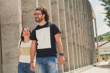 Güzel, genç aşık bir çift sokakta yürüyor, gülümsüyor ve el ele tutuşuyorlar.