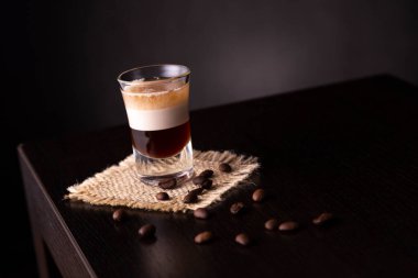 B-52 katmanlı bir kokteyl bardağının üzerine yerleştirilmiş taze kavrulmuş kahve çekirdekleri ve fotokopi alanı.