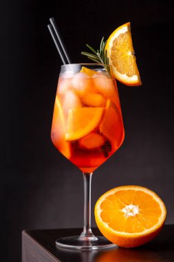 Glass of prosecco and orange liqueur cocktail served in a wine glass, decorated with slices of orange and rosemary branch, placed on a bar counter clipart