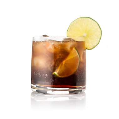 Kahverengi rom, limon suyu, kola ve buzla süslenmiş Küba Libre kokteyli, beyaz arka planda izole edilmiş taze limon dilimi.