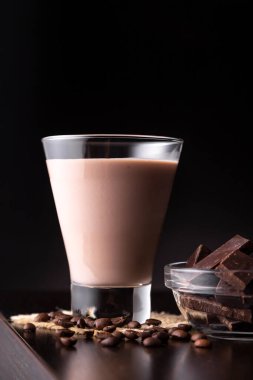 Kahve çekirdekleri ve çikolatayla birlikte bardakta servis edilen İrlanda kremalı kokteyl.