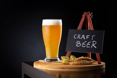 Bir bar tezgahındaki tahtanın üzerine yerleştirilmiş soğuk filtresiz buğday birası; bira tatma sanatı.