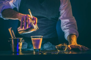 Barmen karıştırıcıda kokteyl hazırlarken barmen kokteyl süzgecini kullanarak Baileys kuyruklu yıldız kokteylini bardaktan cama dökerken...