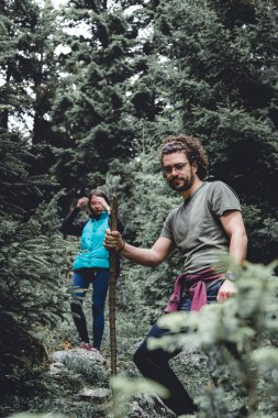 Çiftler açık havada eğleniyorlar, dağlardaki yemyeşil bir ormanda yürüyüş yapıyorlar, doğada boş zamanlarını temiz havada geçiriyorlar, şehir telaşından uzakta.