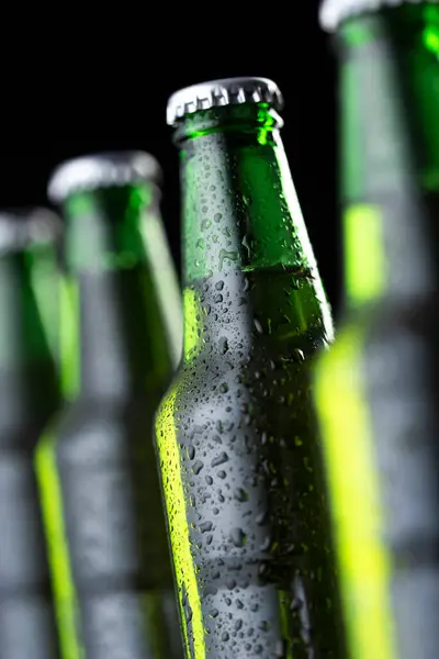 Detail of four bottles of cold beer in a row on a bar counter