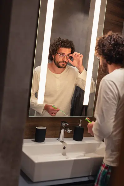 Красивый Молодой Человек Пижаме Стоящий Перед Зеркалом Ванной Комнате Выполняя — стоковое фото