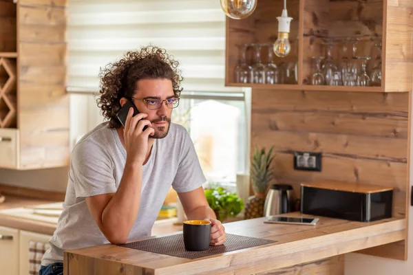 Adam Mutfak Tezgahında Oturuyor Kahve Içiyor Telefonla Konuşuyor Evde Dinleniyor — Stok fotoğraf