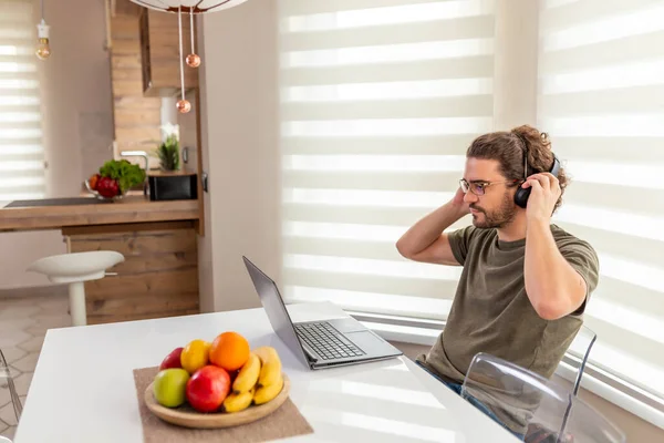 Joven Sentado Mesa Cocina Con Auricular Trabajando Ordenador Portátil Teletrabajo — Foto de Stock