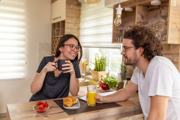 Couple in love relaxing at home in the morning, drinking coffee and having breakfast at kitchen counter