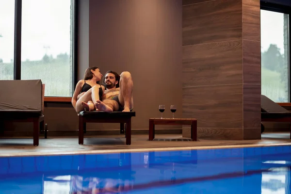 リゾートスパセンターのプールで一緒にリラックスして サンベッドに横たわり 休暇を楽しむ恋のカップル — ストック写真