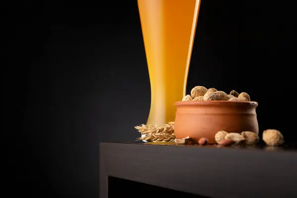 一杯未经过滤的冷麦芽啤酒和一碗未剥皮的花生放在吧台上 — 图库照片