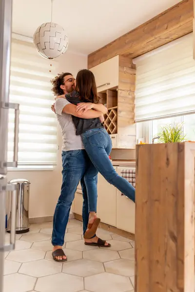 愛の美しい若いカップルは キッチンで踊り 彼氏は彼のガールフレンドを持ち上げて抱きしめ 自宅で楽しくリラックスしている — ストック写真