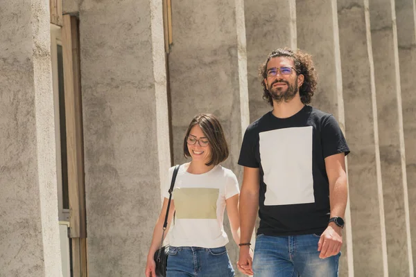 Güzel, genç aşık bir çift el ele tutuşuyor ve şehir caddesinde yürüyor güneşli bir yaz gününün tadını çıkarıyorlar.