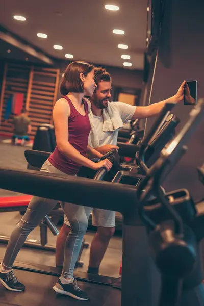 年轻夫妇在健身房锻炼 休息一下 从跑步机上跑来跑去 放松一下 然后自拍 — 图库照片