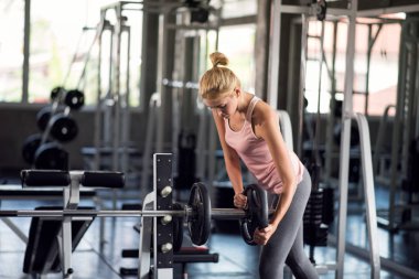 Güçlü bir kadın spor salonunda ağırlık plakasıyla egzersiz yapıyor spor salonunda egzersiz yapıyor.