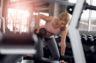 Güçlü kadın spor salonunda dumbbells ile yapıyor