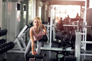 Güçlü kadın spor salonunda dumbbells ile yapıyor