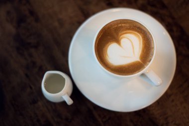 Tahta masada bir fincan sıcak latte sanat kahvesi.