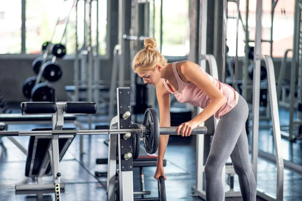 Ισχυρή γυναίκα άσκηση με την πλάκα βάρους μπάρα σε ένα γυμναστήριο c — Φωτογραφία Αρχείου