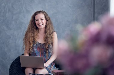 Evde dizüstü bilgisayarla çalışan genç bir kadın. 