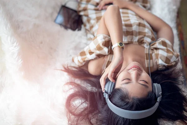 Joven mujer asiática disfrutar escuchando música con auriculares y u — Foto de Stock