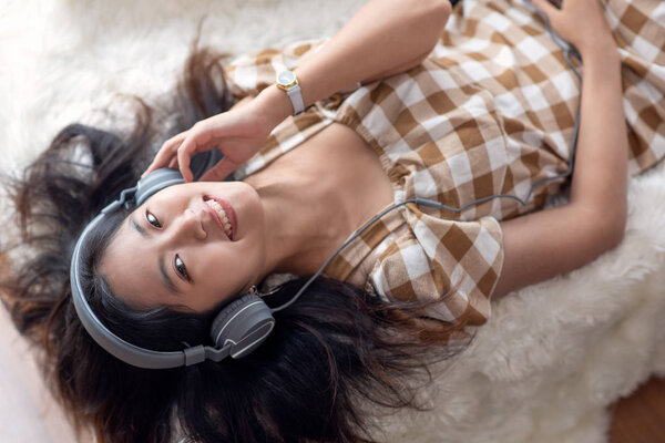 Young Asian woman enjoy listening to music with headphones, happ