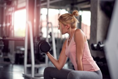 Güçlü kadın spor salonunda dumbbells ile yapıyor